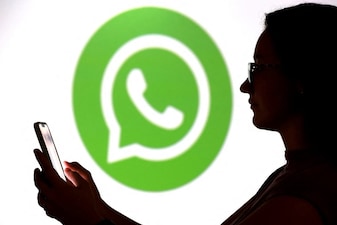 A teenager poses for a photo while holding a smartphone in front of a Whatsapp logo in this illustration taken September 11, 2025. REUTERS/Dado Ruvic/Illustration