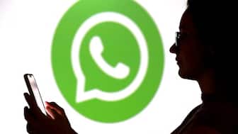 A teenager poses for a photo while holding a smartphone in front of a Whatsapp logo in this illustration taken September 11, 2025. REUTERS/Dado Ruvic/Illustration