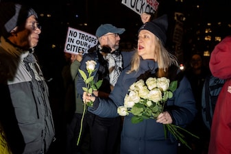 A woman passes out white roses in honor Renee Nicole Good in New York City, US. Reuters