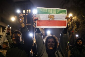A woman holds up a paper print of the "Lion and Sun" pre-Iranian Revolution national flag as demonstrators walk toward the Iranian embassy during a rally in London, Britain. Reuters