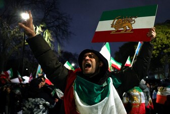 A man gestures while displaying the "Lion and Sun" pre-Iranian Revolution national flag as demonstrators gather outside the Iranian embassy during a rally in support of nationwide protests in Iran. Reuters