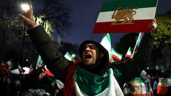 A man gestures while displaying the "Lion and Sun" pre-Iranian Revolution national flag as demonstrators gather outside the Iranian embassy during a rally in support of nationwide protests in Iran. Reuters