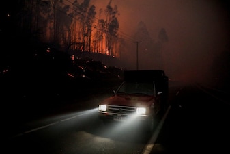 A car drives as fire and smoke rise from a forest fire in the Biobio region. Reuters
