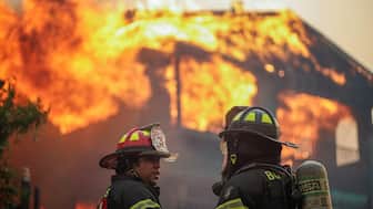 Firefighters stand in front of a burning building in the aftermath of a forest fire in the Biobio region where multiple wildfires prompted emergency evacuations in Concepcion. Reuters