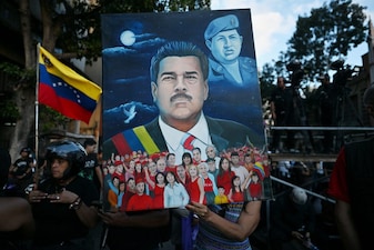 A woman shows a painting depicting ousted Venezuela's President Nicolas Maduro and former President Hugo Chavez (1999-2013) during a demonstration by supporters in Caracas on January 4, 2026, a day after he was captured in a US strike. (AFP)