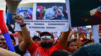A demonstrator holds a picture of ousted Venezuela's President Nicolas Maduro and his wife Cilia Florez during a rally in their support in Valencia, Carabobo state, Venezuela on January 10, 2026. AFP