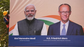 A worker installs a hoarding welcoming German Chancellor Friedrich Merz and Indian prime minister Narendra Modi ahead of their visit in Ahmedabad, India. AP