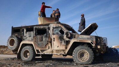 Local youth play atop of a damaged armored vehicle belonging to the Syrian Democratic Forces (SDF) at the site of clashes with Syrian government forces in the village of al-Hol in northeastern Syria's Hasakeh province. AP