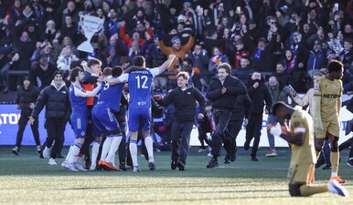 Macclesfield supporters (C) storm the pitch to celebrate the team's victory with players (L) at the end of the English FA Cup third round football match between Macclesfield Town and Crystal Palace at Leasing.com Stadium, Moss Rose in Macclesfield, northern England on January 10, 2026. AFP