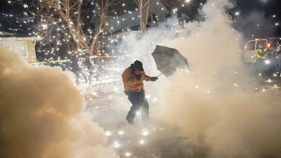 A protesting community member attempts to protect themselves as federal agents fire munitions and pepper balls, as tensions rise after federal law enforcement agents were involved in a shooting incident, in north Minneapolis, Minnesota, US, January 14, 2026. File Image/Reuters