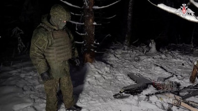 A Russian service member stands next to the remains of a drone, which, according to the Russian Defence Ministry, was downed during the repelling of an alleged Ukrainian attack on the Russian presidential residence in the Novgorod Region, in an unknown location in Russia, in this still image from a video released on December 31, 2025. Reuters File