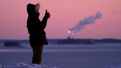 Emma Nadeau, of North Yarmouth, Maine, photographs the pre-dawn scene overlooking Casco Bay on a 1-degree F. morning, Saturday, Jan. 24, 2026, in Portland, Maine. (AP Photo/Robert F. Bukaty)