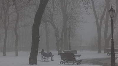 A man sits on a bench on a foggy day in a snow-covered park in Kyiv on January 7, 2026, amid the Russian invasion of Ukraine.- AFP