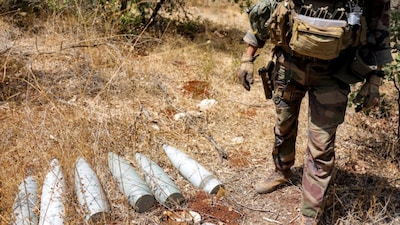 A French peacekeeper of the United Nations Interim Force in Lebanon (UNIFIL) stands by munitions formerly used by Iran-backed Hezbollah at a position that was held by the group in the Khraibeh Valley in el-Meri in south Lebanon on August 27, 2025.- AFP