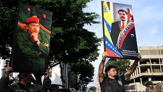 Venezuelan government supporters hold photographs of Venezuela's late President Hugo Chavez and President Nicolas Maduro, after  Donald Trump said the US has struck Venezuela and captured Maduro, in Caracas, on January 3. Reuters