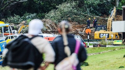 A couple looks at a landslide while a search is underway by local emergency services for missing people at Mount Maunganui in Tauranga. A landslide smashed into a campsite in rain-swept northern New Zealand leaving multiple people missing, police and rescuers said. AFP