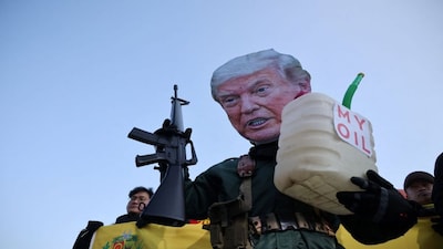 An activist, wearing a cutout mask depicting US President Donald Trump, holds a toy gun and a container with the words, 'My Oil' during an anti-Trump rally to condemn the US conducting a military act on Venezuela to capture its President Nicolas Maduro and his wife Cilia Flores, in central Seoul, South Korea. Reuters