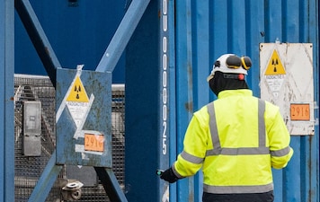 A worker prepares to unload several cylinders of uranium from the Russian cargo ships(Photo by Sameer Al-DOUMY / AFP)
