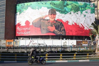 Iranians ride their motorbike past a huge banner of former Iran Islamic Revolutionary Guard Corps (IRGC) Quds Force commander Qasem Soleimani ahead of the sixth anniversary of his assassination Iraq, at Valiasr Square in Tehran, on December 31, 2025. Soleimani was killed on January 3, 2020, in a targeted US airstrike at Baghdad airport in Iraq. (Photo by ATTA KENARE / AFP)