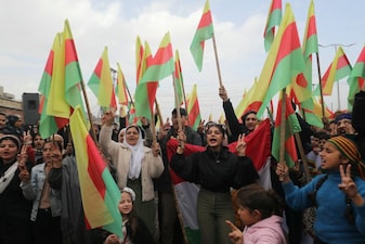 Syrian Kurds lift up flags and flash the V for victory sign during a demonstration in the city of Hasakeh in northeastern Syria, on February 1, 2026, as they rally behind the Kurdish forces and support the recent agreement with the government. Syrian Kurds rallied in the northeast city February 1, in a show of solidarity ahead of the implementation of a recent deal with the government. Damascus and Kurdish forces reached a comprehensive agreement on January 30, to gradually integrate the Kurds' military and civilian institutions into the state, after under-pressure Kurds ceded territory to advancing government forces in recent weeks. (Photo by Delil SOULEIMAN / AFP)