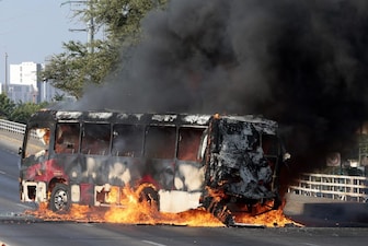 A member of the Gereal Attorney's Office stands guard near a bus set on fire by organised crime groups in response to an operation in Jalisco to arrest a high-priority security target, at one of the main avenues in Zapopan, state of Jalisco, Mexico. AFP