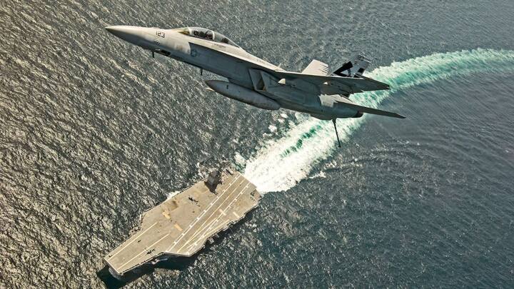An F/A-18F Super Hornet jet flies over the USS Gerald R. Ford as the U.S. Navy aircraft carrier tests its EMALS magnetic launching system.  File- Reuters
