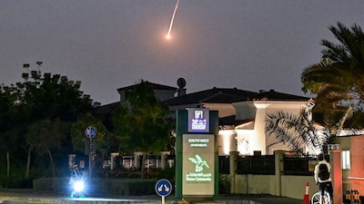 A cyclist watches as a projectile falls over Dubai on February 28, 2026.- AFP
