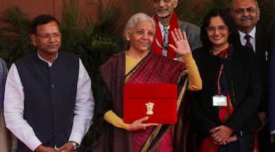 India's Finance Minister Nirmala Sitharaman waves as she holds a folder bearing the Government of India's emblem, while posing with her officials before leaving her office to present the annual federal budget in parliament, in New Delhi, India, February 1, 2026. REUTERS