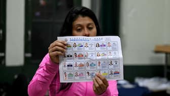 An election official shows a ballot as she counts votes after polls closed at the Pilar Jimenez school polling station during the presidential election in San Jose on February 1, 2026.