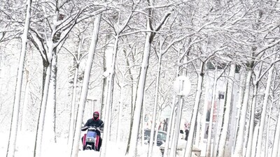 A food delivery person rides an electric scooter through the snow covered Gaudenzdorfer Guertel boulevard as winter strikes Vienna, Austria with snow and freezing temperatures on February 20, 2026. (Photo by Joe Klamar / AFP)