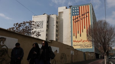 People walk past an anti-US mural on a street in Tehran, Iran. Washington continues to slowly and steadily build-up its military forces in the region, causing concerns that the US will strike the Islamic Republic. Reuters