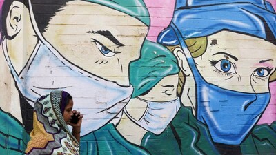 A woman walks past a coronavirus (COVID-19) themed mural on a street in Mumbai, March 28, 2023. File Photo/Reuters