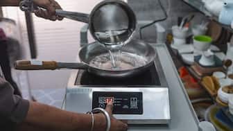 A cook prepares food on an induction cooktop amid LPG shortages affecting restaurants, in Mumbai, March 11, 2026. PTI