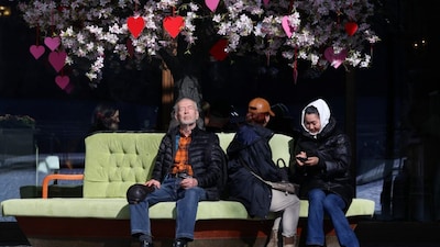 People sit on a sofa beneath a decorated tree outside a cafe on a sunny day in central Moscow, Russia, March 16, 2026. Reuters