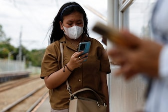 A woman uses her smartphone while waiting for a train at a station in South Tangerang, on the outskirts of Jakarta, Indonesia, January 15, 2025. REUTERS/Willy Kurniawan