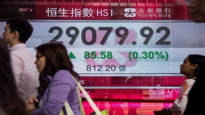 Pedestrians walk past a display showing the Hang Seng Index in Hong Kong. (File/AFP)
