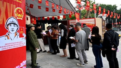 People queue before casting their ballots inside a voting station in Hanoi on March 15, 2026. AFP