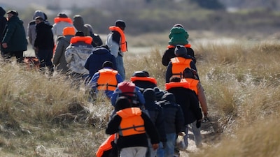 Migrants trying to reach Britain, walk on a beach shore in Gravelines, northern France, Wednesday, March 18, 2026. AP