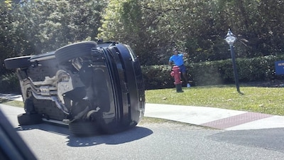 Golfer Tiger Woods stands by his overturned vehicle in Jupiter Island, Fla., on Friday, March 27, 2026. AP