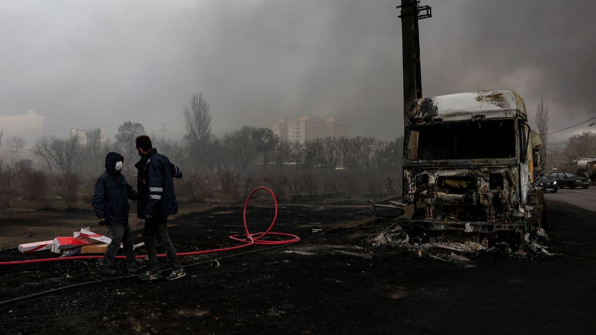 People stand near a destroyed vehicle as smoke rises after a reported strike on Shahran fuel tanks amid the US-Israeli conflict with Iran in Tehran, Iran, on March 8, 2026. (Photo: Majid Asgaripour/WANA via Reuters) 