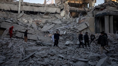 People stand in rubble at the site of an Israel and US strike on a police station in Tehran, Iran, on Tuesday. Reuters