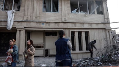 Residents stand on a street beside damaged residential buildings near Niloufar square in Tehran during the ongoing joint US-Israeli military campaign on Iran on March 2, 2026. (AFP)