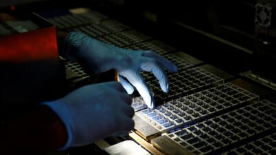 A technician checks the machine with a flashlight at a solar panel manufacturing hub in Greater Noida, on the outskirts of New Delhi India, October 23, 2024. REUTERS/Priyanshu Sing