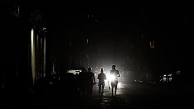 People walk on a street without electricity during a nationwide blackout in Havana on March 21, 2026. (AFP)