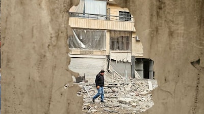 A man walks along a street strewn with building debris at the site of an overnight Israeli airstrike that targeted a neighborhood in Beirut’s southern suburbs on March 25, 2026.
