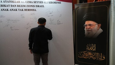 A man signs a temporary tribute wall for the late Iranian supreme leader Ayatollah Ali Khamenei at the residence of Iranian ambassador in Jakarta, Indonesia. AP