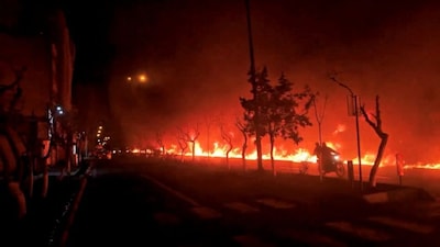 A motorcycle passes by fire burning along Tehran's Koohsar Boulevard, Iran, in this screengrab from video obtained from social media and released on March 8 amid the conflict. (Reuters)
