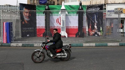 A motorist rides past the dummy models of Iranian missiles installed along the roadside at the Valiasr Square, in Tehran. The war is nearing the one-month mark, with no signs of it abating. AFP