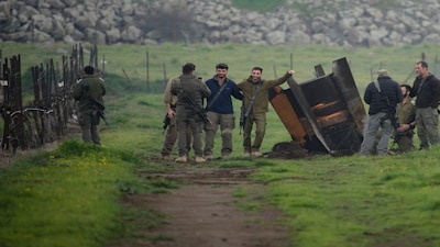 Israeli soldiers take photographs next to a fragment of a missile fired from Iran, and intercepted by Israeli defence system, embedded in an open field in the Israeli-controlled Golan Heights. AP
