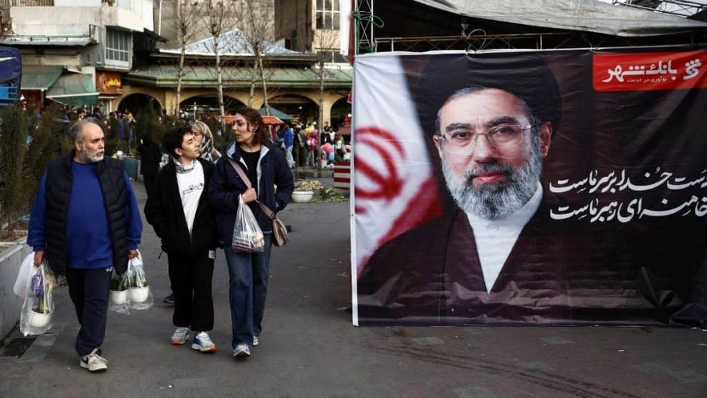 People walk next to a banner with a picture of Iran's new Supreme Leader, Mojtaba Khamenei, at Tajrish Bazaar, ahead of Nowruz, the Iranian New Year, amid the US-Israeli conflict with Iran, in Tehran, Iran, March 19, 2026. File Image/WANA via Reuters